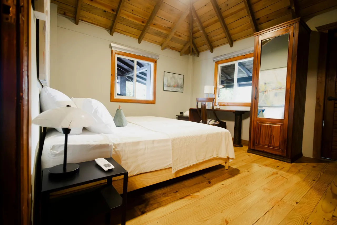 Habitación de La Suiza del Mogote con cama doble y techo de madera
